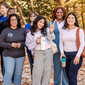 Students posing outside with an autumn background.